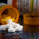Opioid pills spill from bottle.