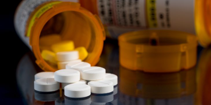 Opioid pills spill from bottle.