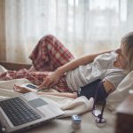 Old woman in bed looking at screen of laptop and consulting with a doctor online at home, telehealth