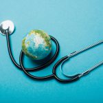 Globe and stethoscope on blue background, world health day concept