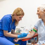 Preparation for blood test with senior woman by female doctor medical uniform on the table in white bright room. Nurse pierces the patient’s arm vein with needle blank tube.