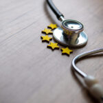 Closeup image of stethoscope and five stars on wooden table with copy space.