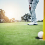 Ground, golf hole and man with golfing club on course for game, practice and training for competition. Professional golfer, sports and male athlete hit ball on grass for winning, score or tee stroke