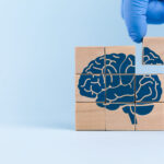 A doctor’s hand arranges wooden cubes with a brain icon. Concept of well-being and cognitive performance, brain function. Understanding neurodegenerative disorders.