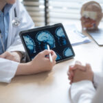 Medical Moment: Understanding Brain Tumors Doctor explaining brain MRI scan results on digital tablet.